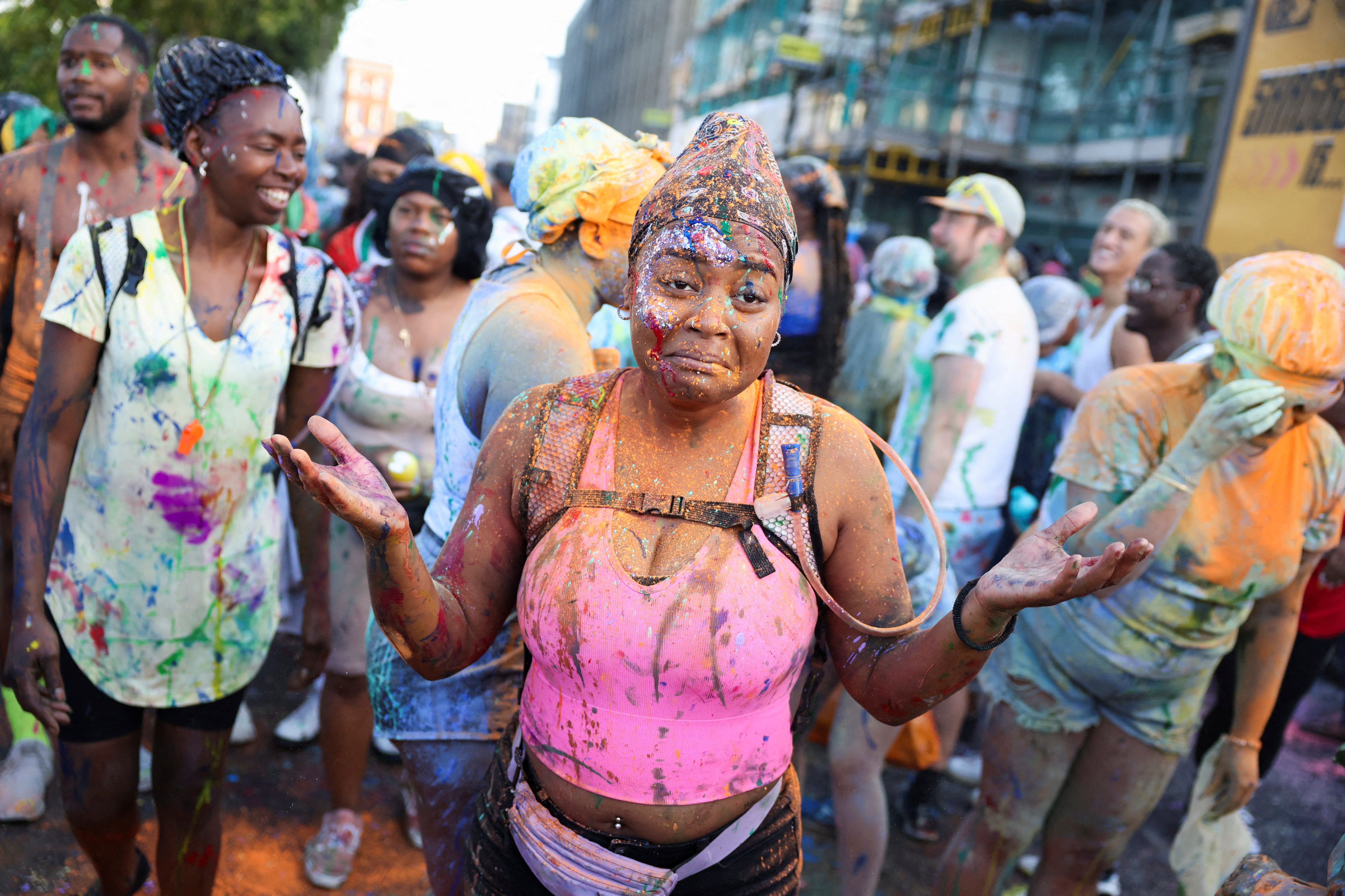 A woman reacts after being covered in paint during the ‘J’Ouvert’ celebrations at sunrise during Notting Hill Carnival, in London