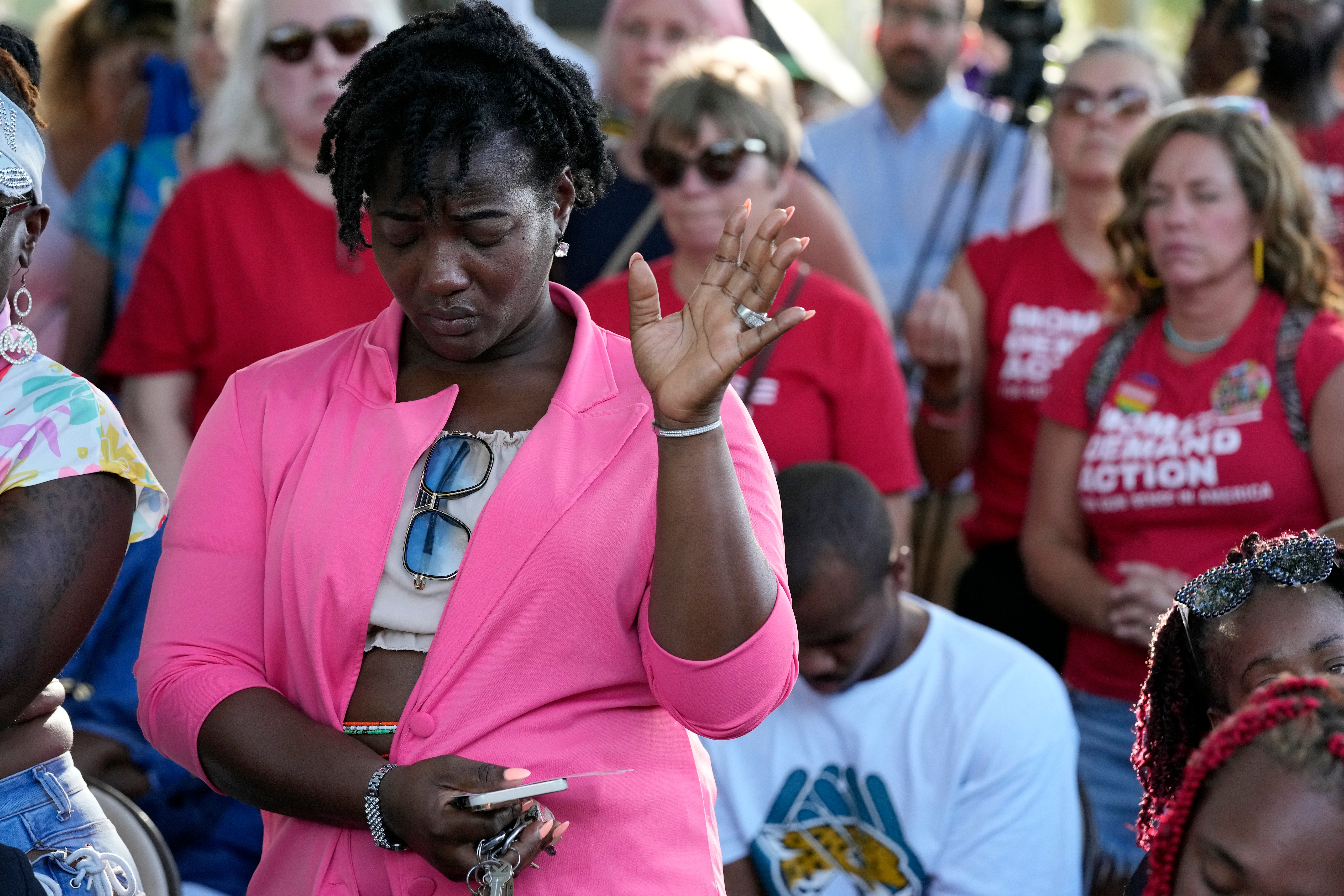 A woman attending a vigil for the victims of Saturday's mass shooting bows her head in prayer on Sunday