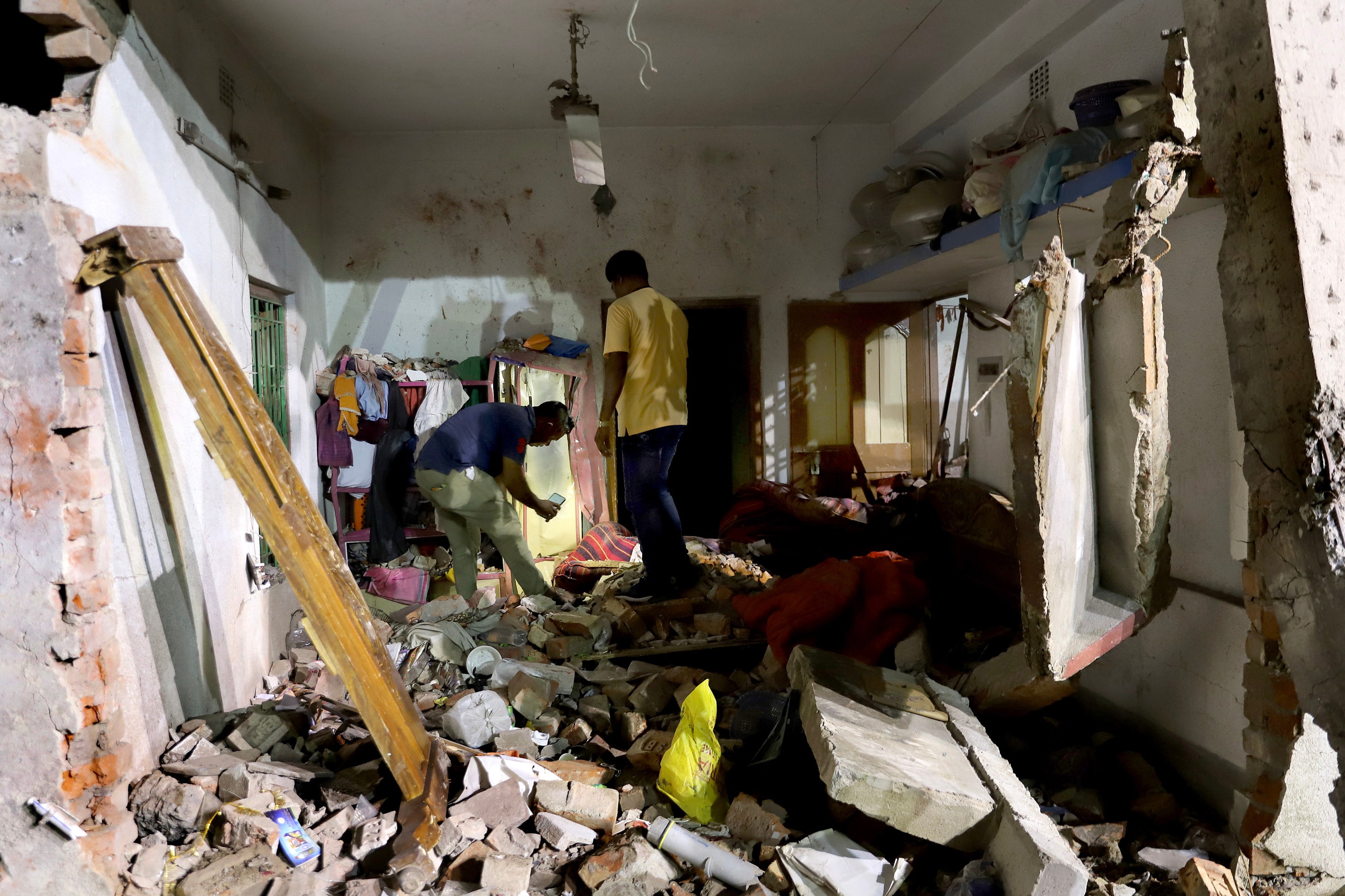 Residents inspect their damaged home after a massive explosion occurred at a firecracker factory in Duttapukur village