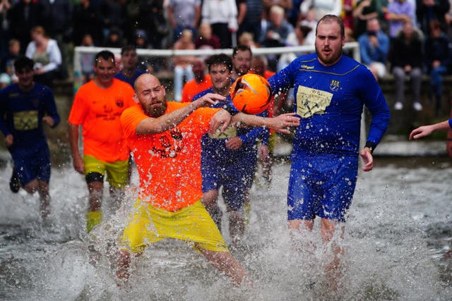 Footballers from Bourton Rovers fight for the ball during the annual traditional River Windrush football match (Ben Birchall/PA)