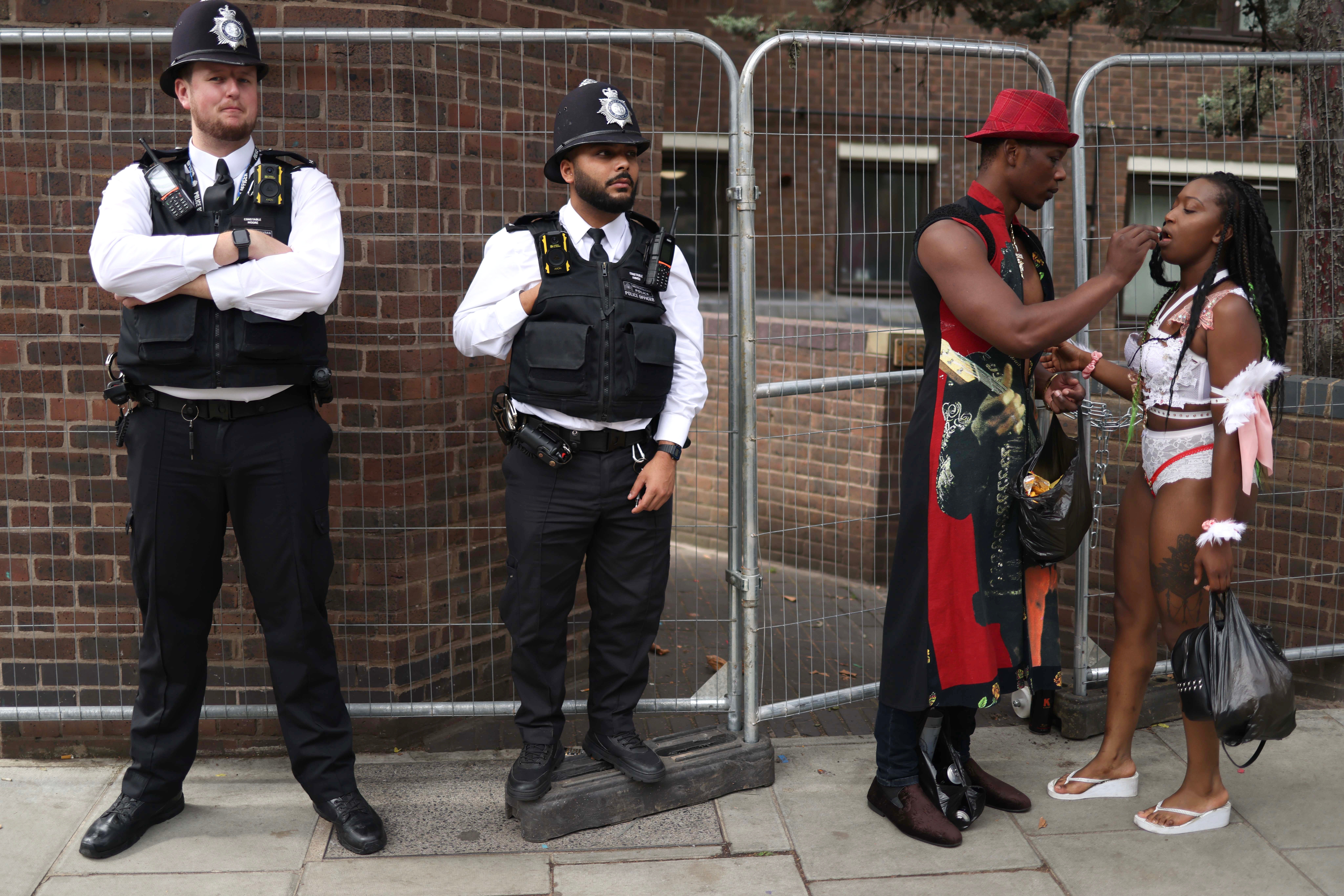 Carnival goers stand next to police officers