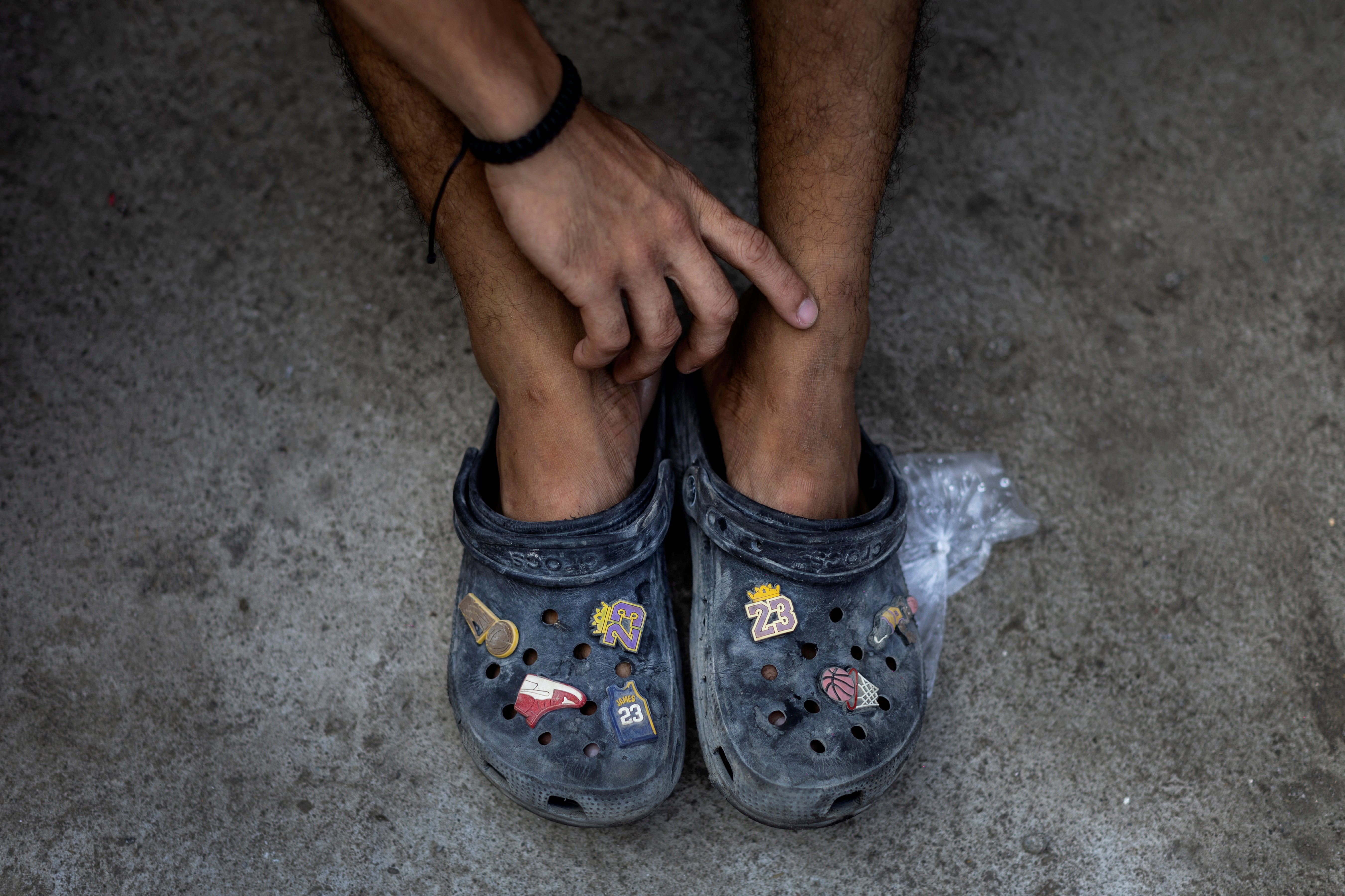 A teenage boy wears basketball-themed rubber slippers while watching a basketball game at the community-built court Baryo Aroma in Tondo, Manila