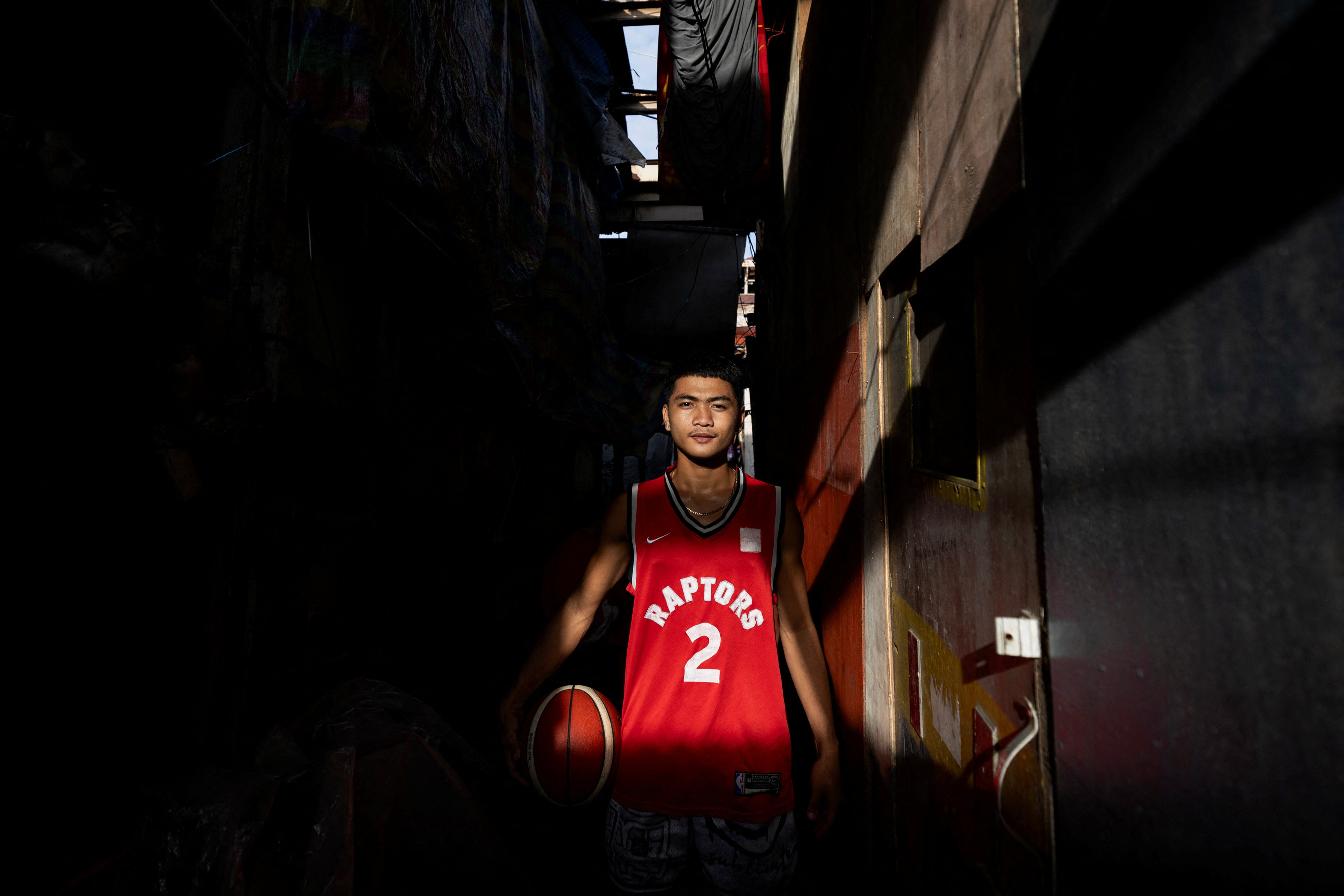 Jessie Conde, 18, a regular player at the community-built court Baryo Aroma, poses for a portrait outside his home in Tondo, Manila