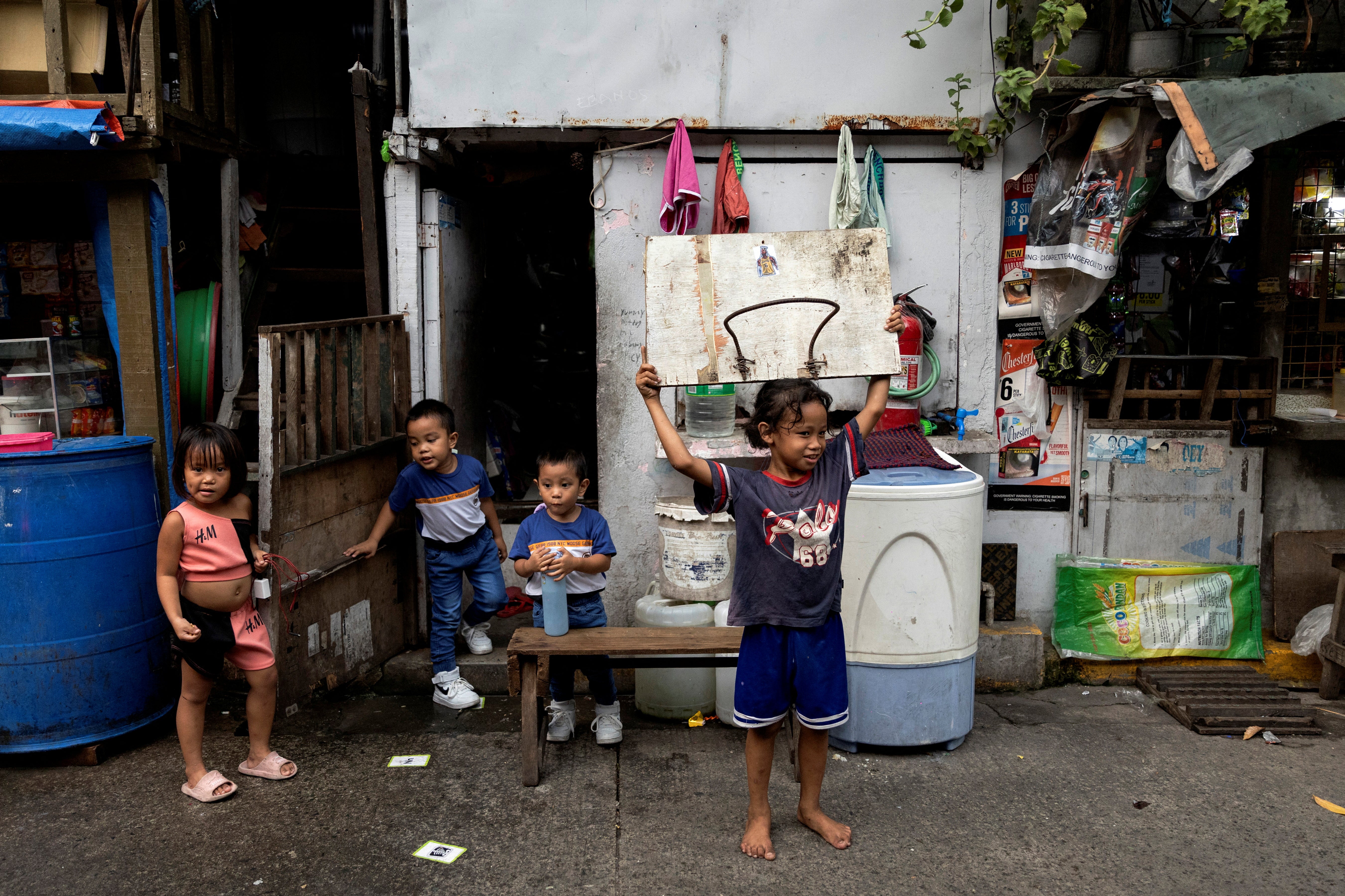 A boy carries a makeshift basketball rim while playing with friends in Manila