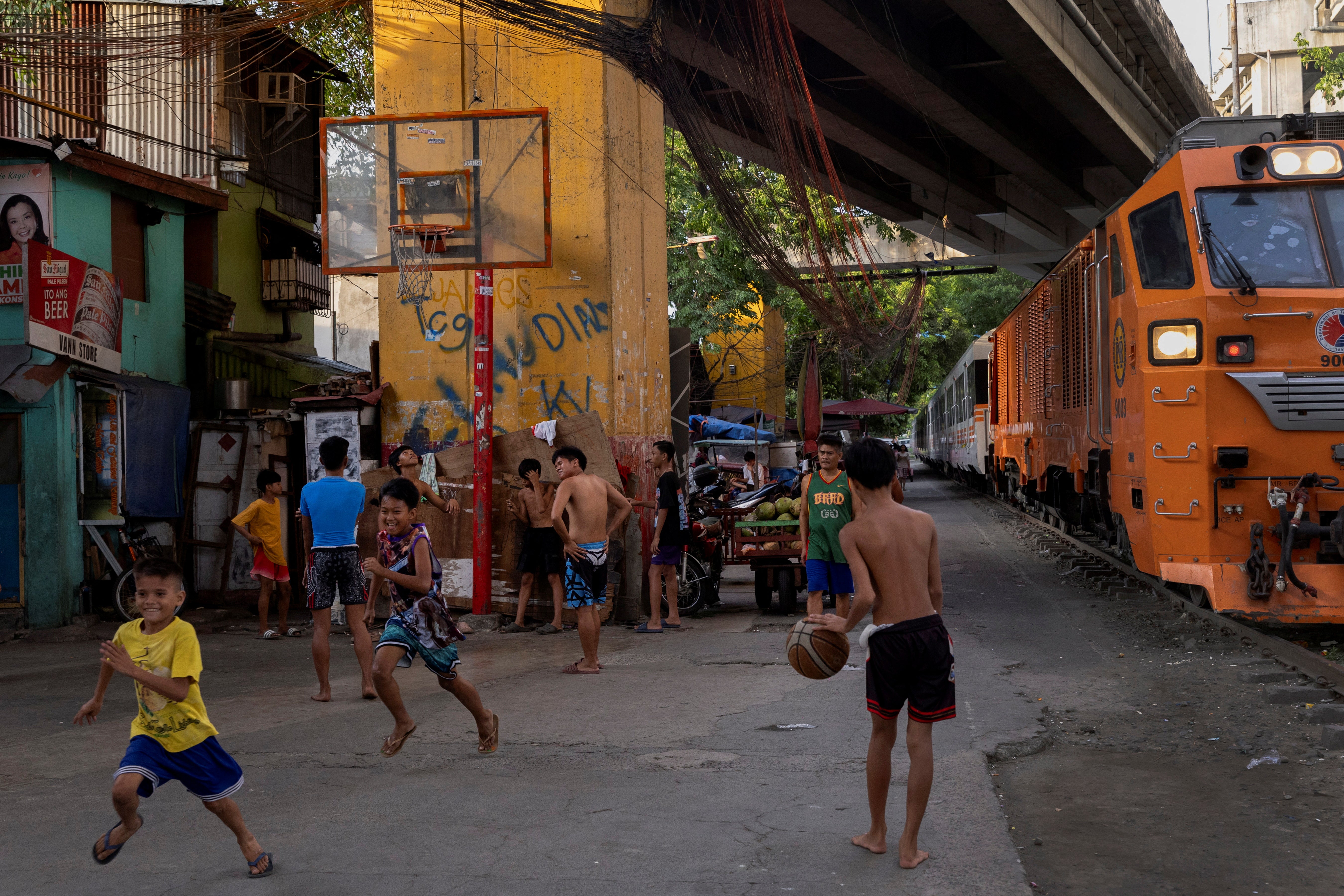 Boys play basketball as a train passes by in Pandacan, Manila