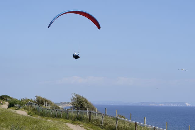 A person paraglides over the cliffs above Boscombe beach in Dorset (Andrew Matthews/PA)