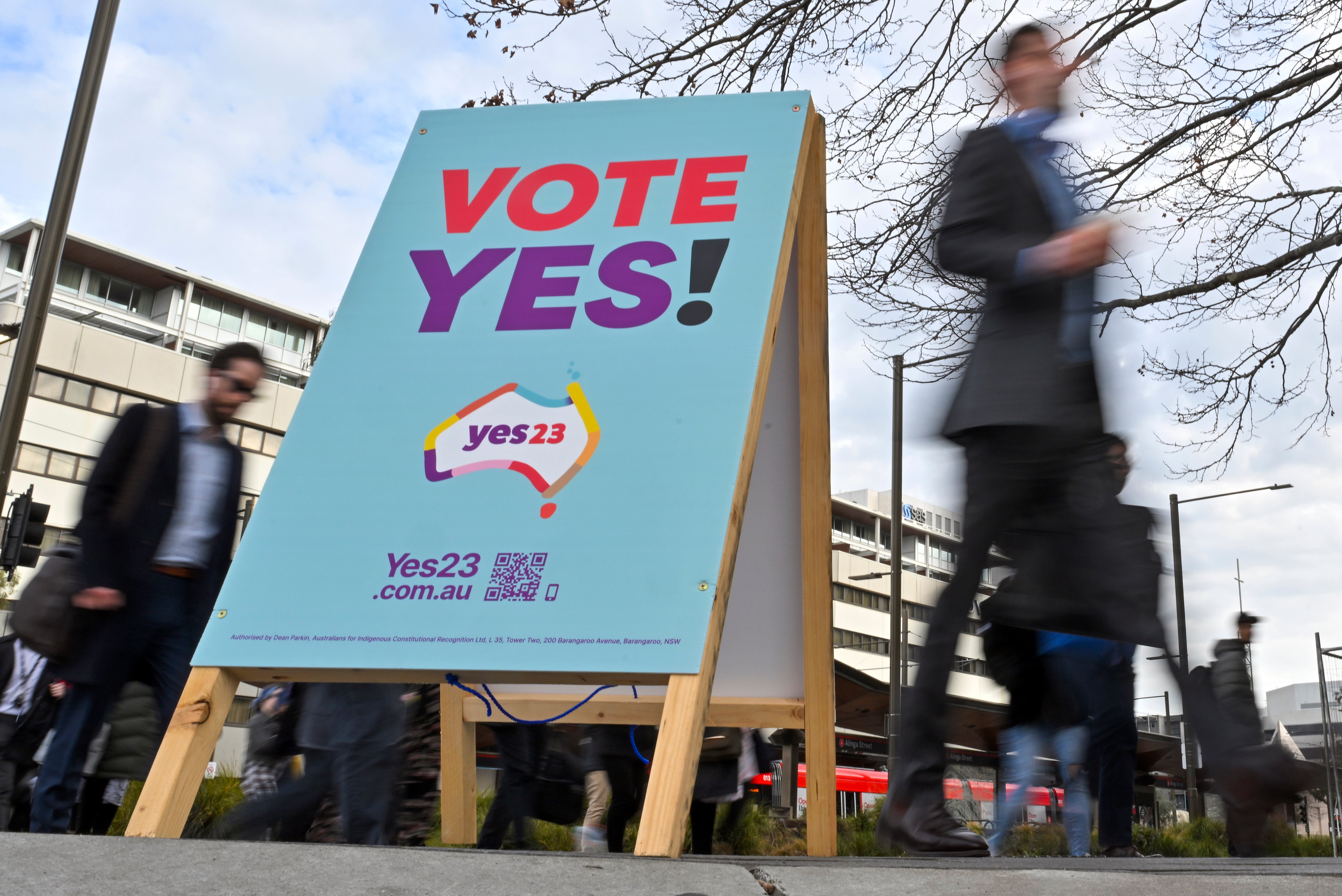 Commuters walk past a vote ‘yes’ stand for the upcoming Voice referendum at the Civic Bus Interchange in Canberra on 30 August