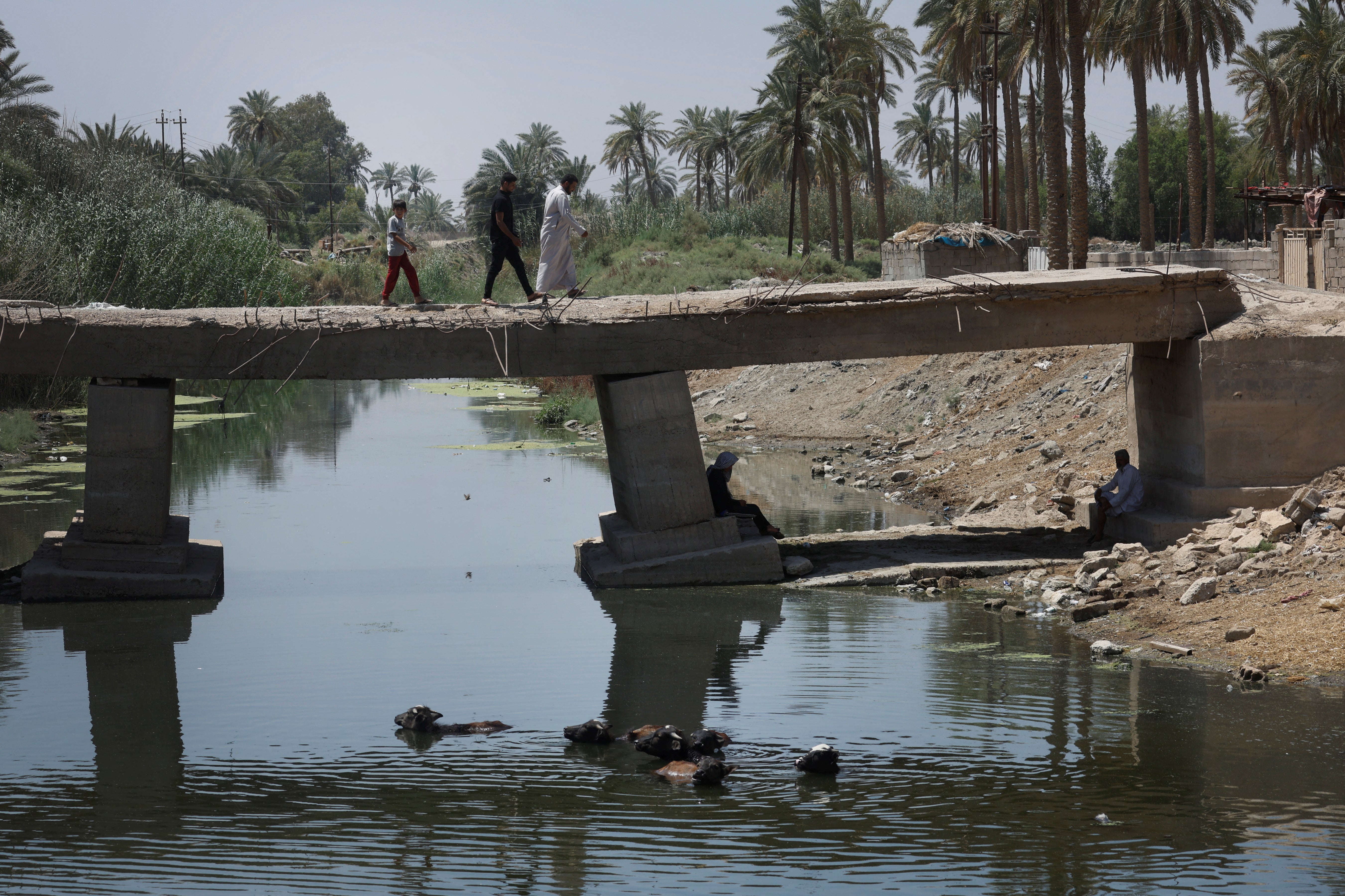 Mustafa and his father Ahmed Abdul Hussein cross a bridge over the Al-Shallal river