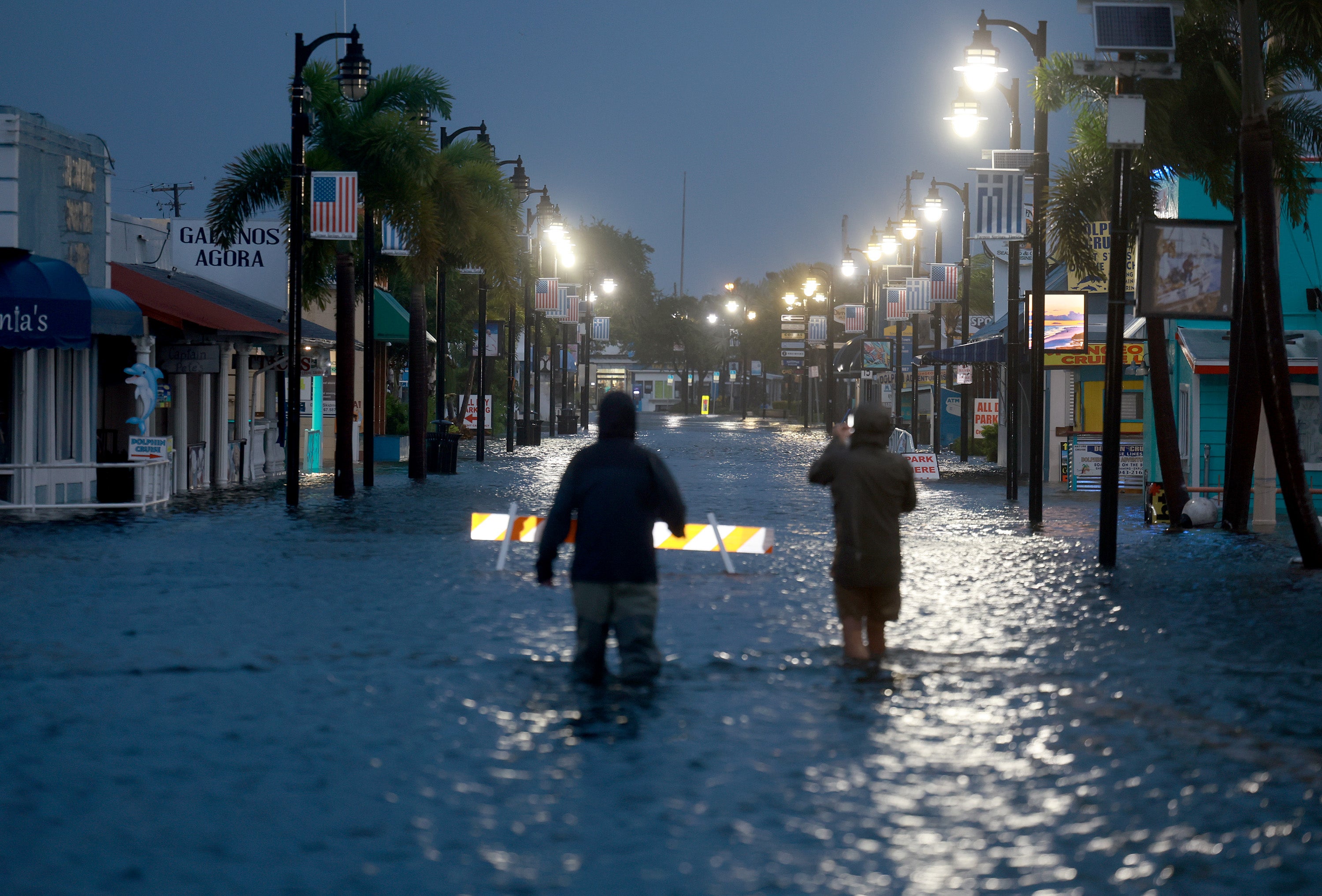 Reporters wade through flood waters as it inundates the downtown area after Hurricane Idalia passed offshore on August 30, 2023 in Tarpon Springs