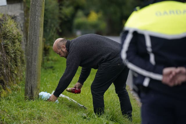 A member of the public lays a teddy bear at the scene where a man, woman and infant boy died in a road crash in Co Tipperary. The single vehicle collision occurred shortly before 9pm on Tuesday when a car hit a wall in the Windmill Knockbulloge area of Cashel (Niall Carson/PA)