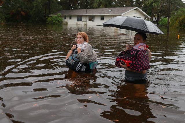 Makatla Ritchter (L) and her mother, Keiphra Line wade through flood waters after having to evacuate their home when the flood waters from Hurricane Idalia inundated it on 30 August 2023 in Tarpon Springs, Florida