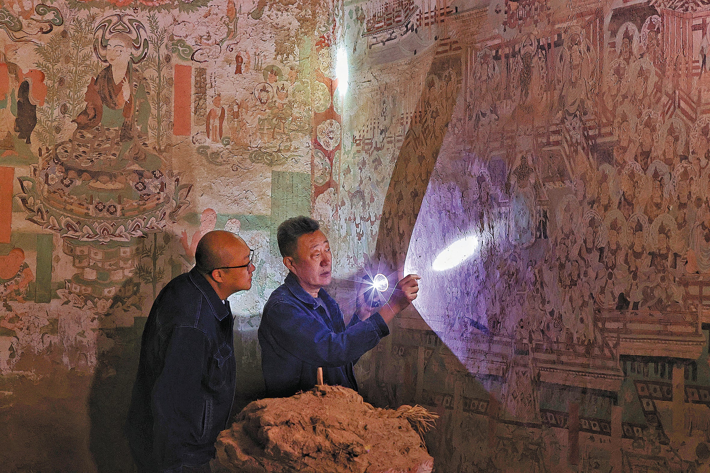 Li Bo (right), a veteran restorer of the Dunhuang Academy, leads a colleague in examining murals in one of the Yulin Caves at Guazhou county near Dunhuang, Gansu province