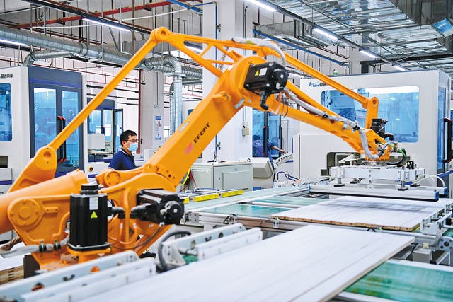 <p>An employee oversees a smart robot processing furniture parts at a production facility in Ganzhou, Jiangxi province, in May, 2023</p>