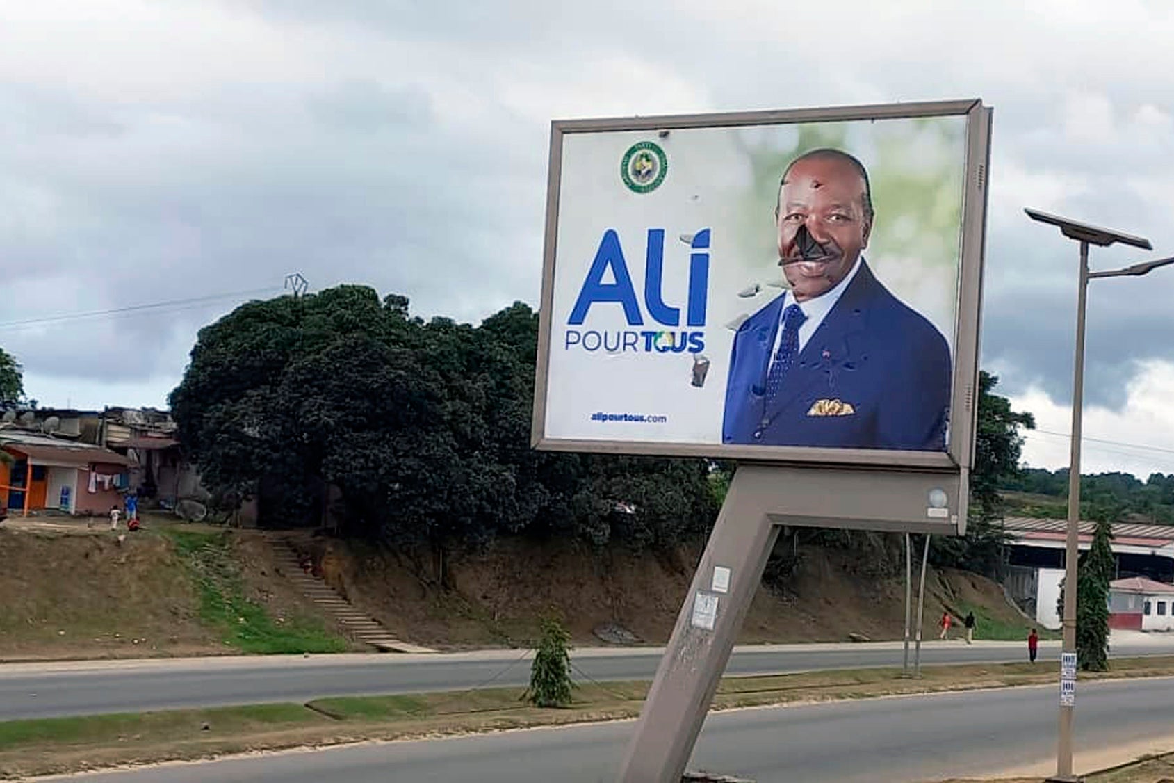 A defaced billboard of Gabon president Ali Bongo Ondimba is seen on an empty street of Libreville