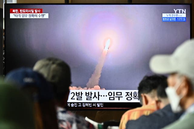 <p>People watch a television showing a news broadcast with a photo of a North Korean missile test on 31 August</p>