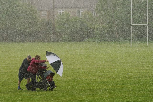 People seek shelter from a heavy rain shower in a park in Terenure, Dublin (PA).