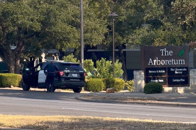 <p>A police officer stands outside Arboretum Shopping Center following a shooting incident</p>