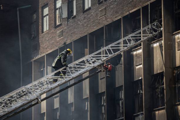 <p>A firefighter climbs a ladder as they extinguish a fire in an apartment block in Johannesburg on 31 August 2023</p>