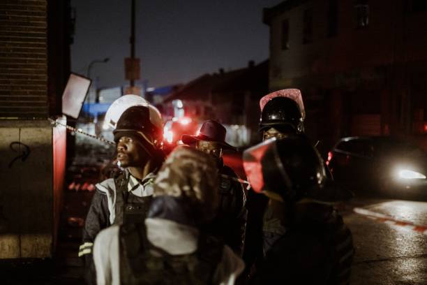 <p> A group of private security guards gather near the entrance of a burned apartment block in Johannesburg on 31 August 2023</p>