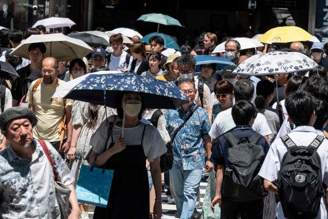 <p>People use umbrellas and parasols to seek relief from the heat while walking outside Shinjuku station, Japan</p>