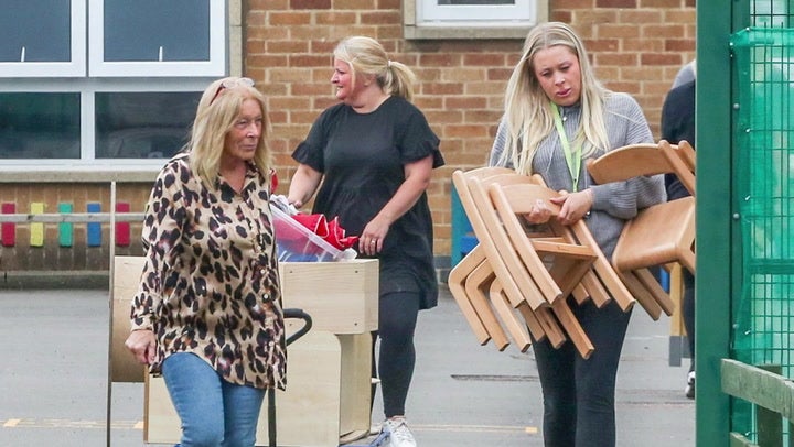 People leave the school in Leicester with chairs and other items after it was closed