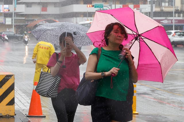<p>People walk with umbrellas in Taipei as Typhoon Haikui approaches</p>
