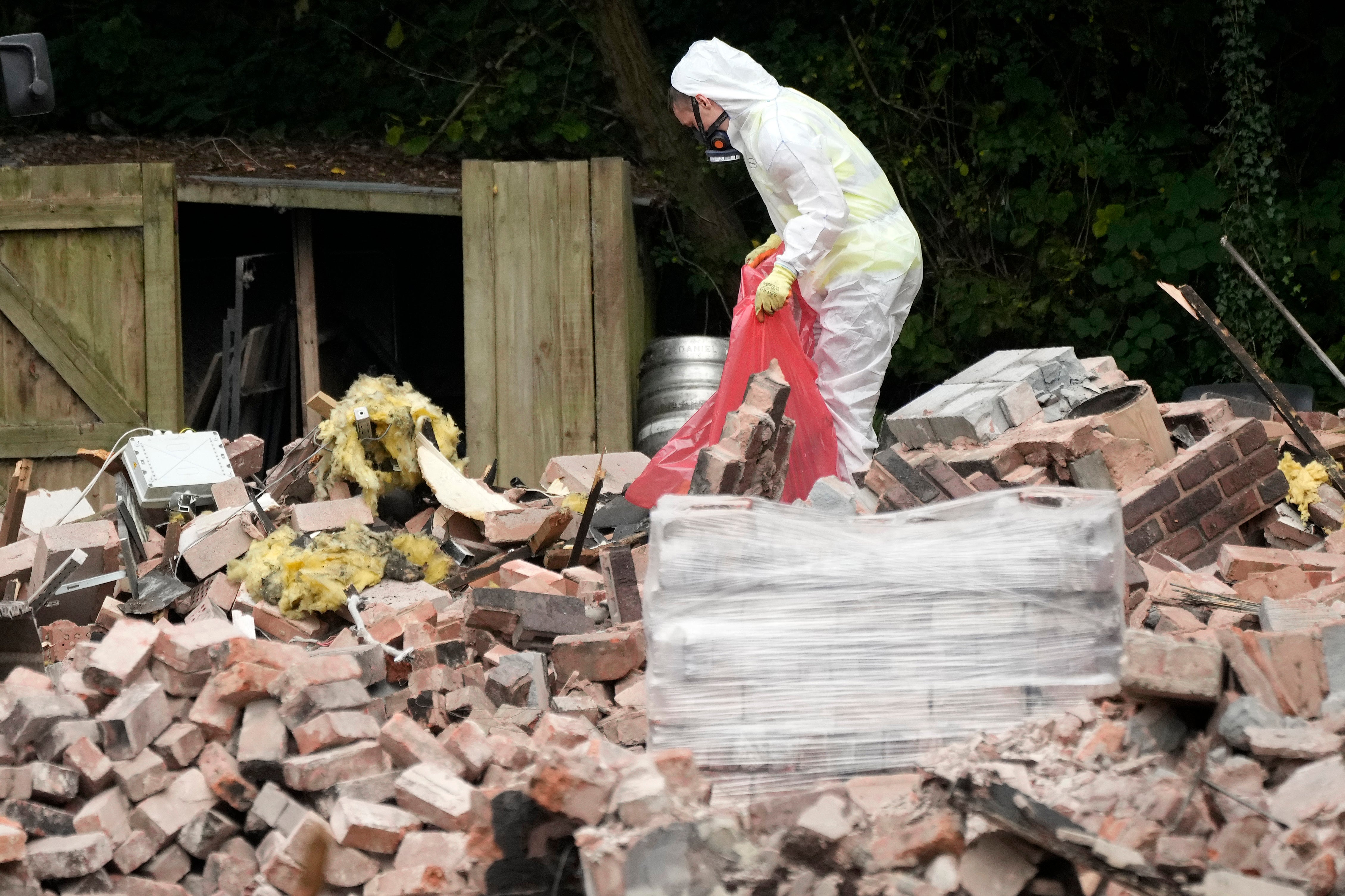 Workers remove dangerous materials from the ruins of the demolished Crooked House pub in August