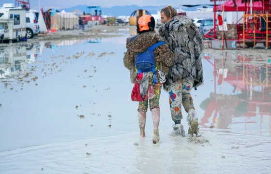 Festivalgoers walk through the mud at Burning Man