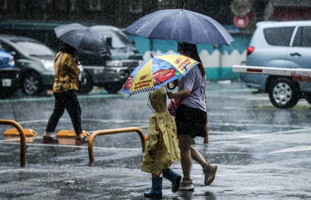 People hold umbrellas while walking on the street in the rain in Keelung after Typhoon Haikui hits Taiwan on 4 September 2023