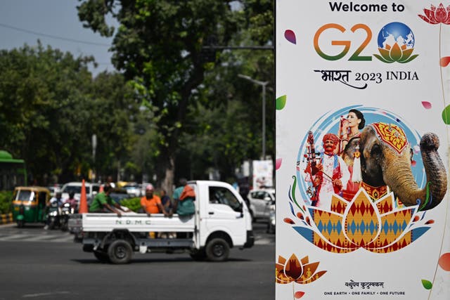 <p>Commuters make their way past a billboard installed along a street ahead of the two-day G20 summit in New Delhi </p>