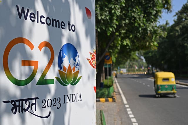<p>An auto-rickshaw drives past a billboard installed along a street ahead of the two-day G20 summit in New Delhi</p>