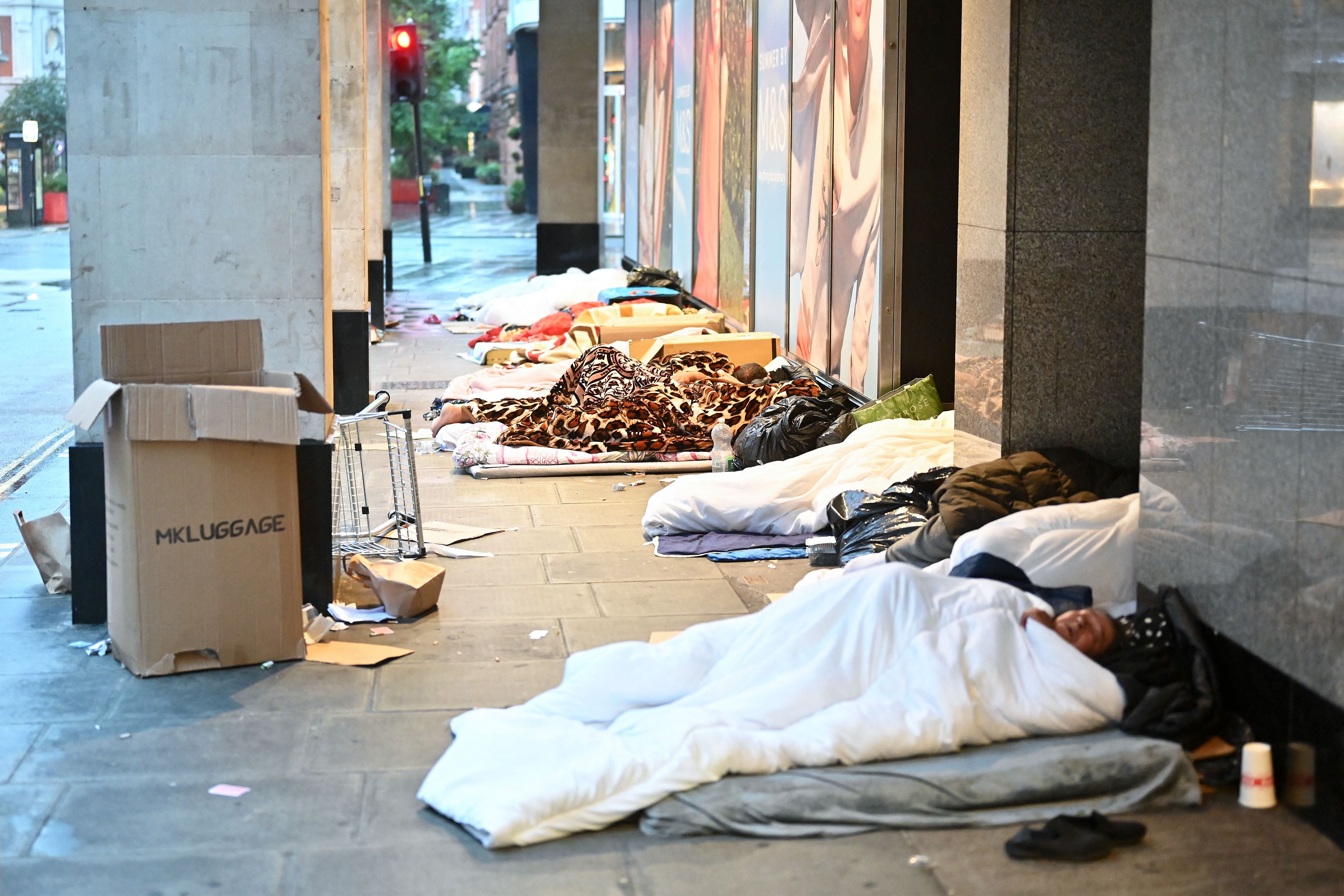 Rough sleepers lay in their makeshift beds outside closed shops, at daybreak on Oxford Street in London on August 2, 2023