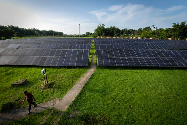 <p>An employee walks away from solar panels near a hydrogen plant at Oil India Limited in Jorhat, India</p>
