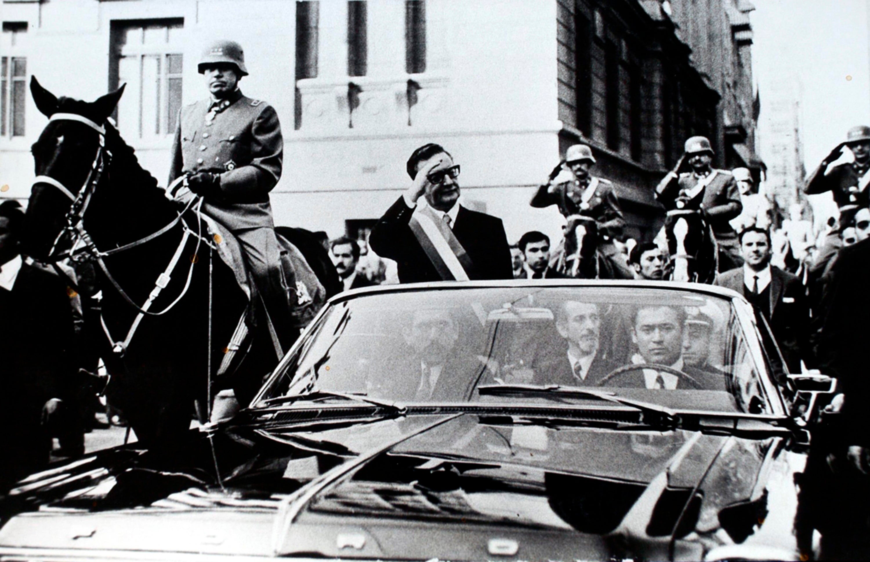 <p>Chilean President Salvador Allende salutes from an open vehicle as General Augusto Pinochet rides on horseback alongside him in Santiago, in May 1972</p>