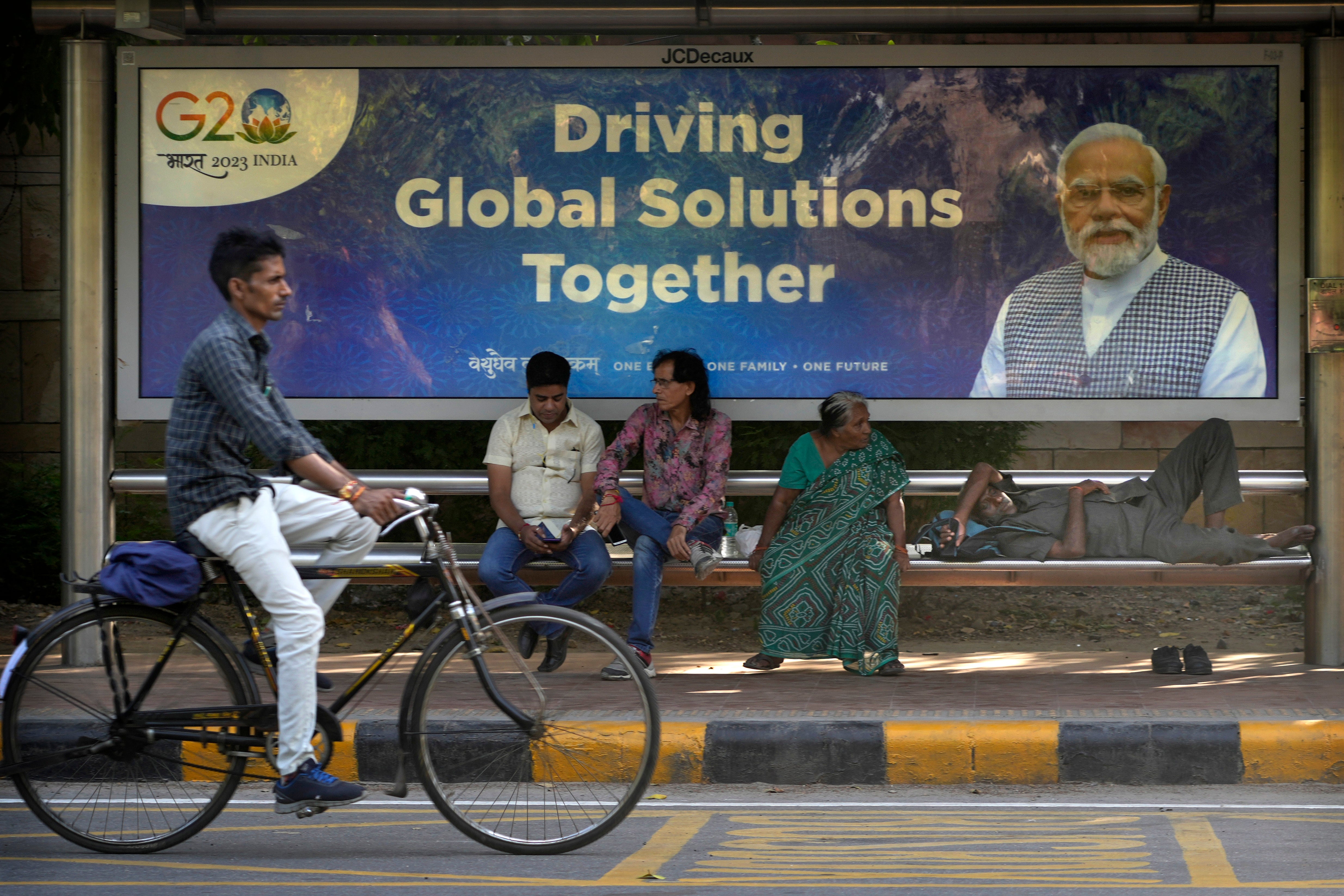 A cyclist rides past a bus waiting shelter with a poster of Indian Prime Minister Narendra Modi ahead of this week's summit of the Group of 20 nations in Delh