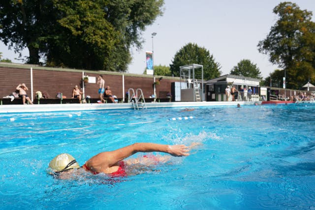 A woman does the front crawl at the idyllic setting of the Jesus Green lido (Joe Giddens/ PA)