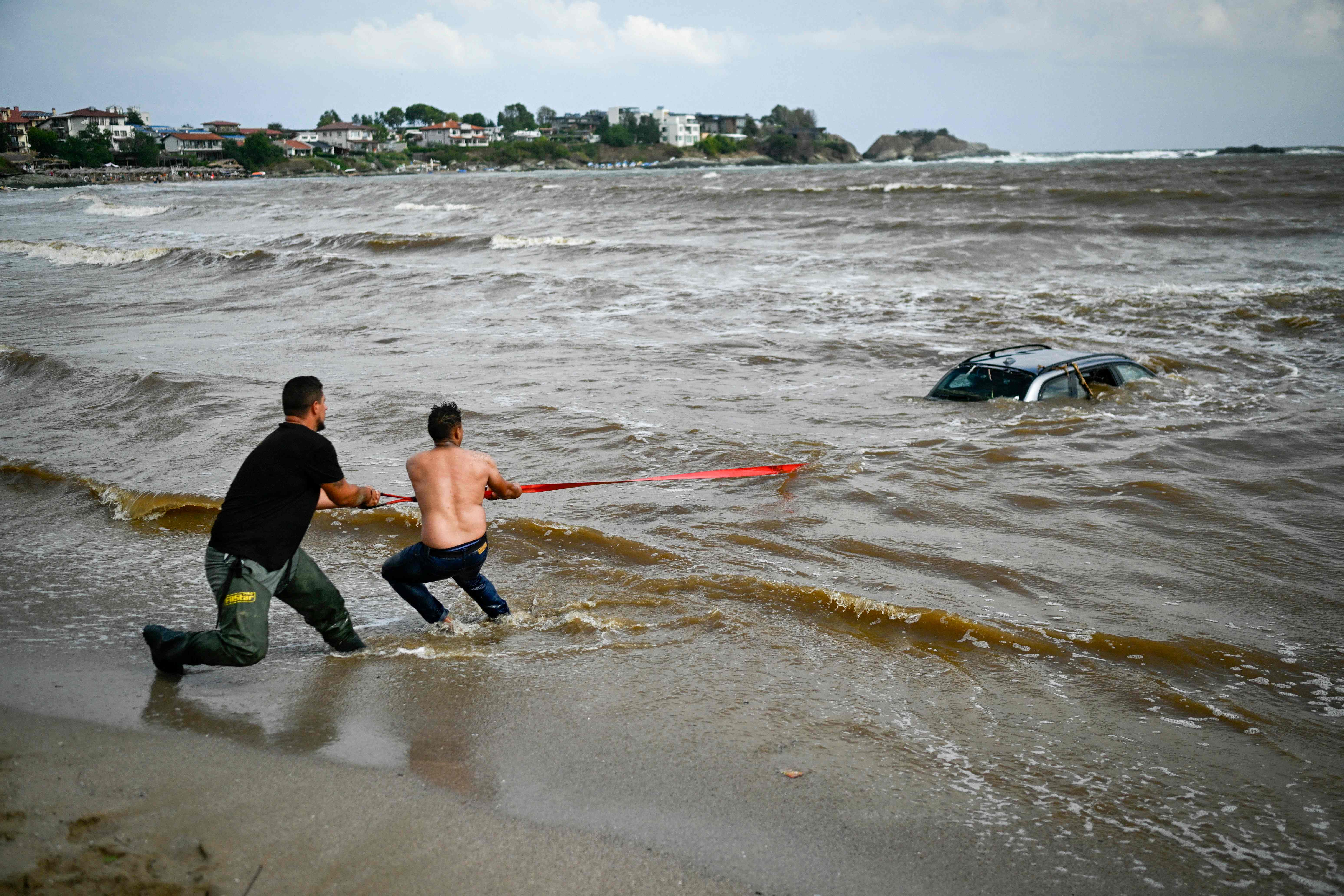 People try to pull out a car submerged in the sea at Arapia camping site near Tsarevo along the Bulgarian Black Sea coast