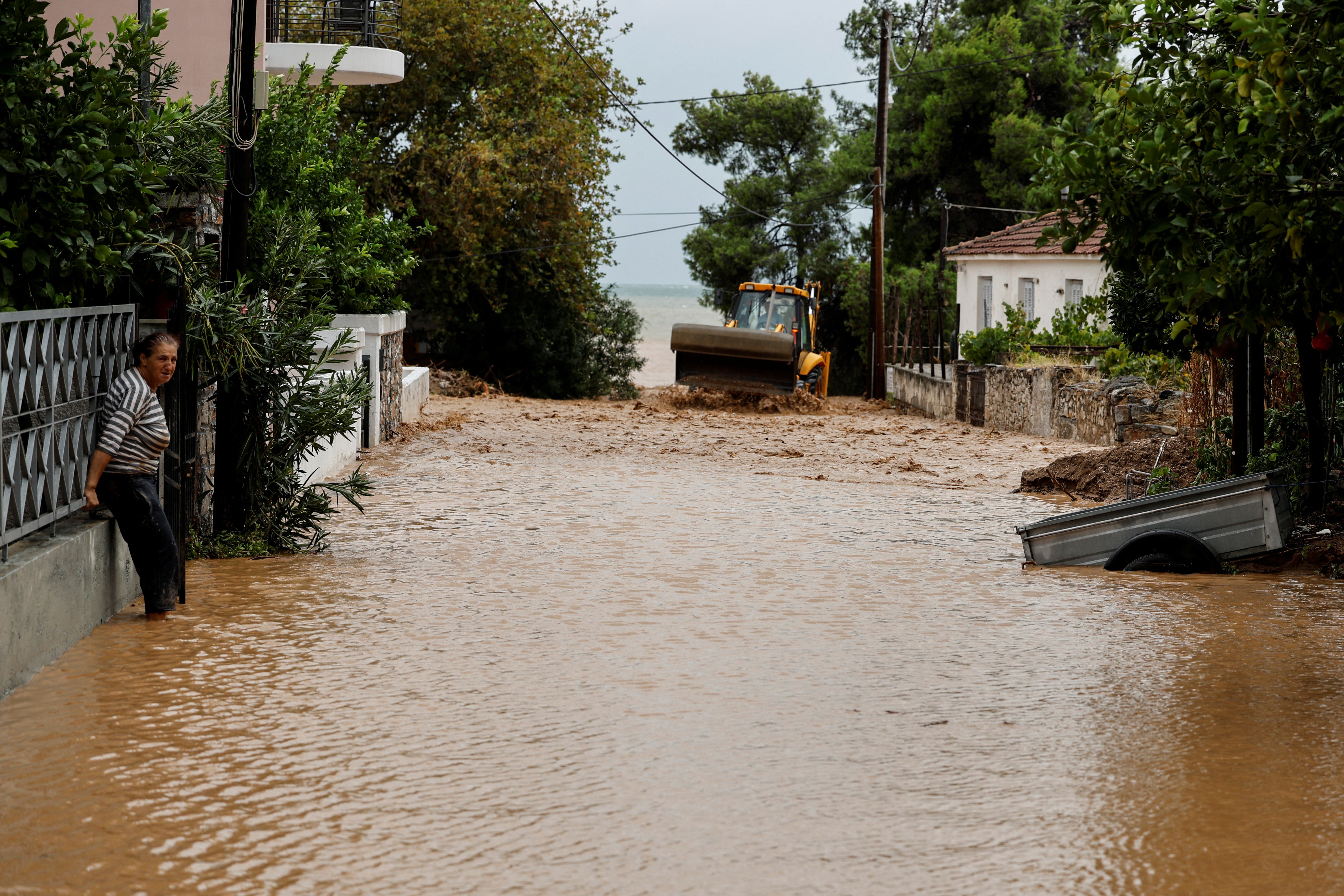 A woman stands in floodwater by her house after torrential rains destroyed the infrastructure and caused flooding in the area, in Agria, Pelion, central Greece