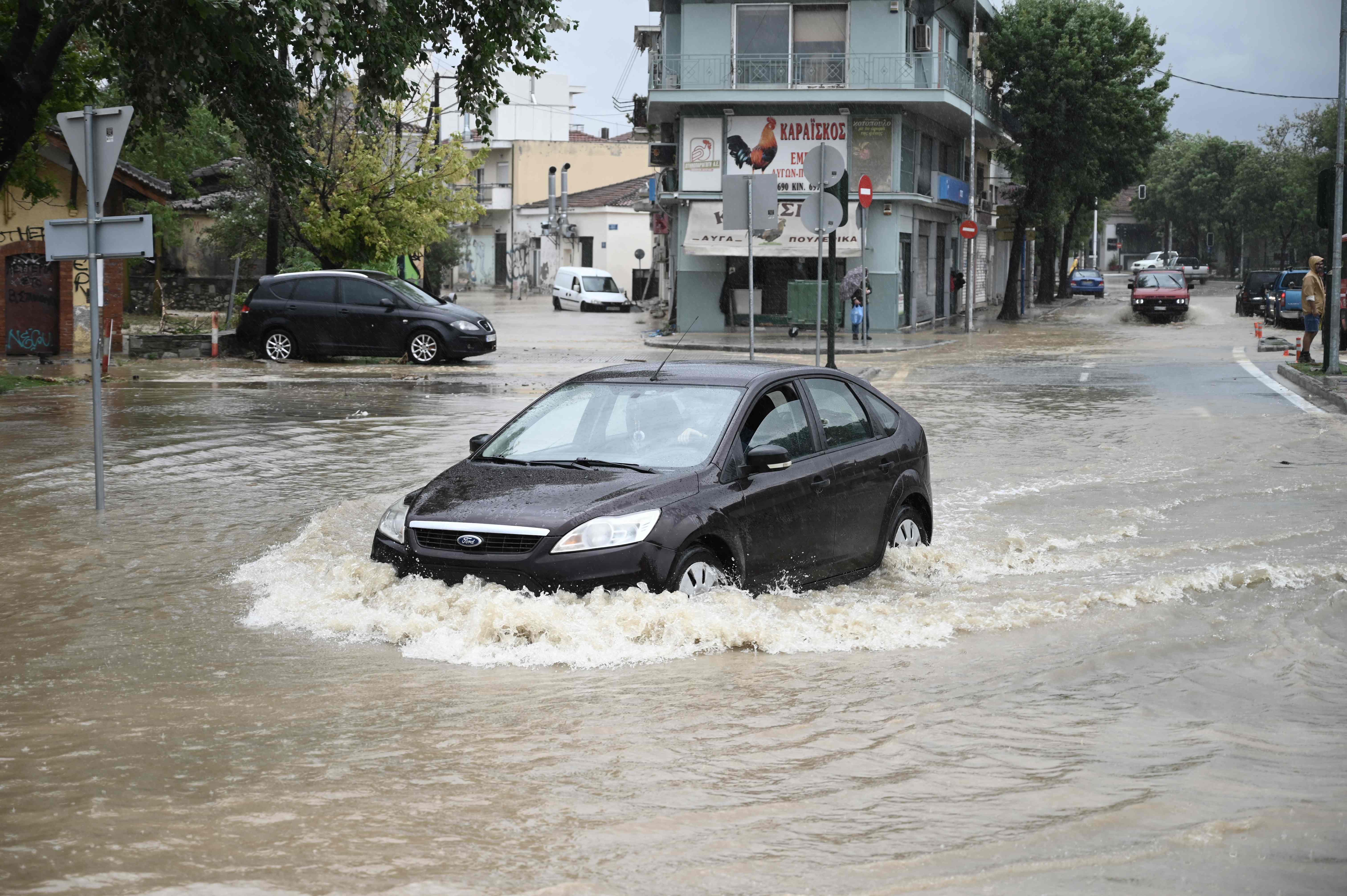 A vehicle crosses a flooded road in the city of Volos, central Greece