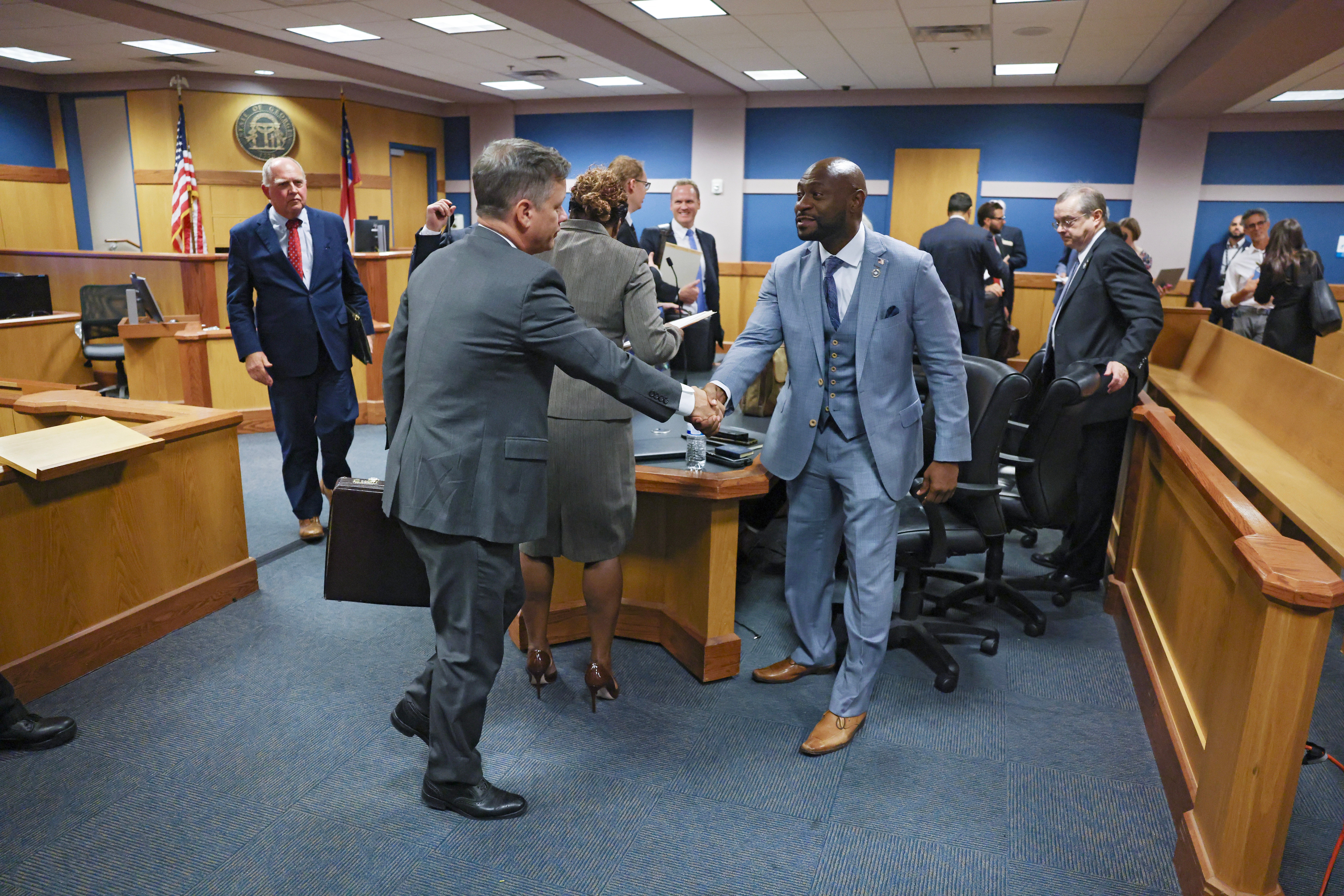 Brian Rafferty, left, who is defending Sidney Powell, and Fulton County proscutor Nathan Wade, right, shake hands after Superior Judge Scott McAfee rejected attempts from Ms Powell and Kenneth Chesebro to sever their cases from one another in a Georgia election interference trial.