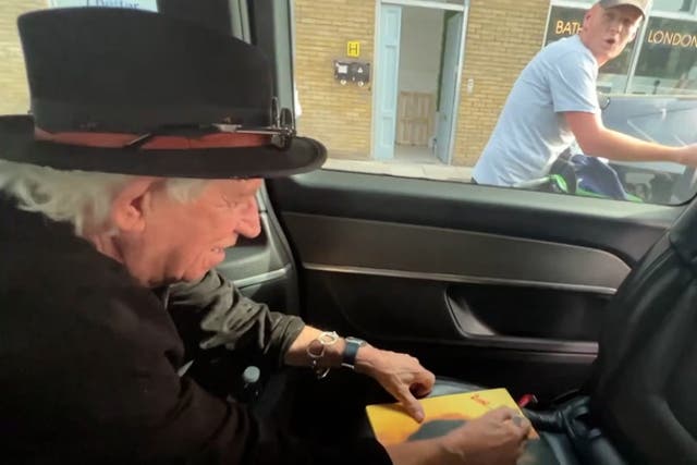<p>Rolling Stones’ Keith Richards jokes with cyclist as he signs autograph for him in taxi at traffic lights.</p>