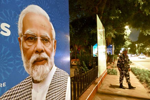 Indian security personnel stands guard next to G20 communication billboard with a portrait of India' prime minister Narendra Modi