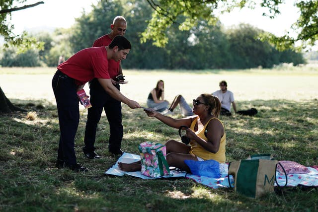 Firefighters hand out leaflets about how to stay safe in the hot weather at Hampstead Heath in London (Jordan Pettitt/PA)