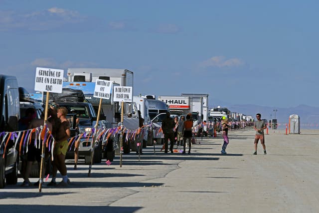 <p>Festivalgoers stand outside of their cars as they wait for traffic to move while exiting the Burning Man festival </p>