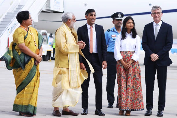 UK Prime Minister Rishi Sunak and his wife Akshata Murty (C) are met on the tarmac by dignitaries including the Indian Minister of State