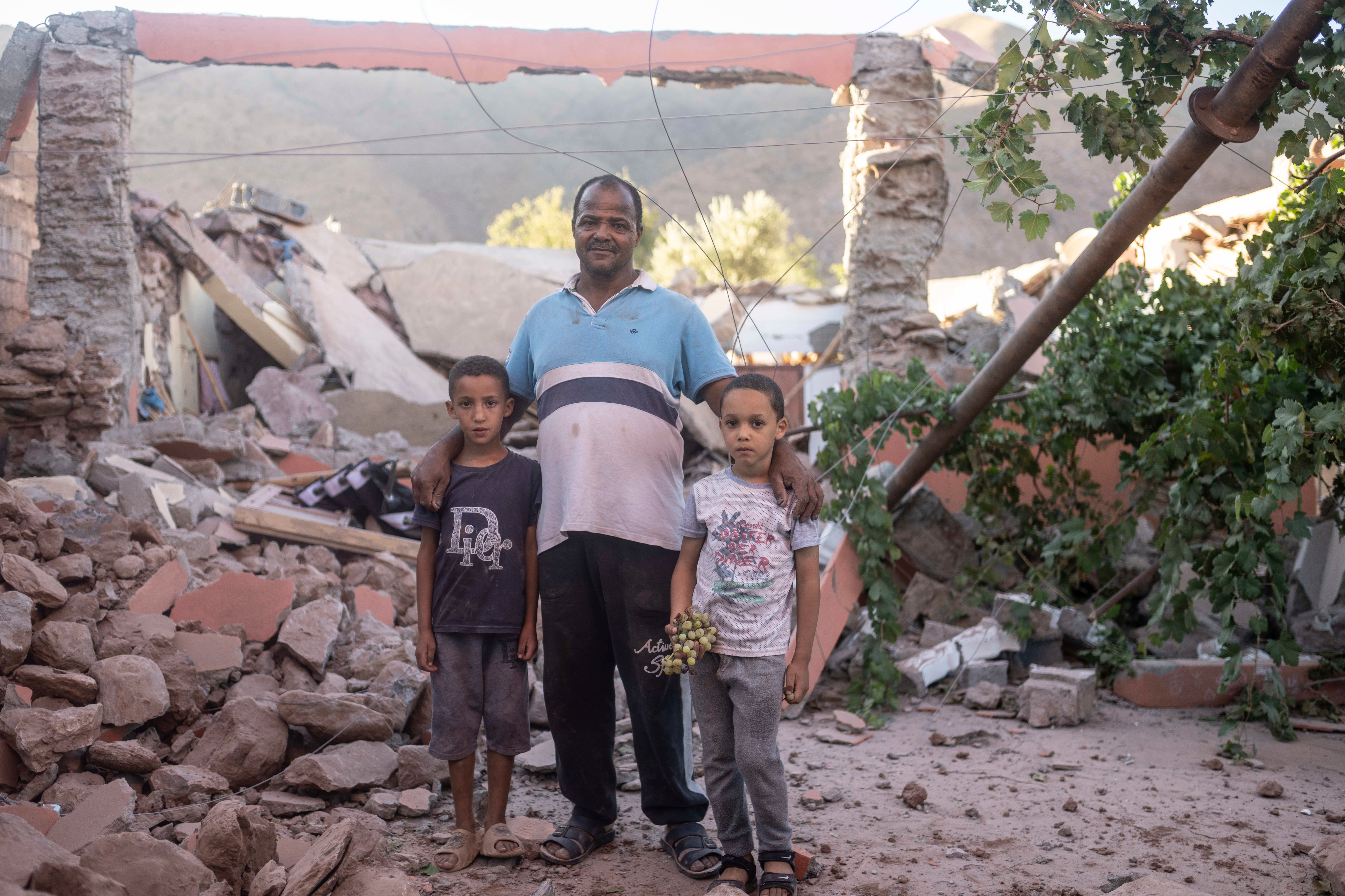 Mohammed Elhmatif and his sons, Rayan, right, and Ali, stand amid the rubble of their home in Ijjoukak village, near Marrakech