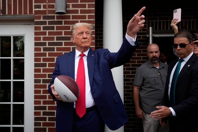 <p>Donad Trump tosses footballs to a crowd at a fraternity house at Iowa State University on 9 September. </p>