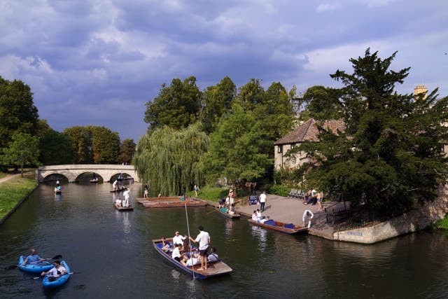 Stormy skies overhead as people enjoy punt tours along the River Cam in Cambridge (PA)