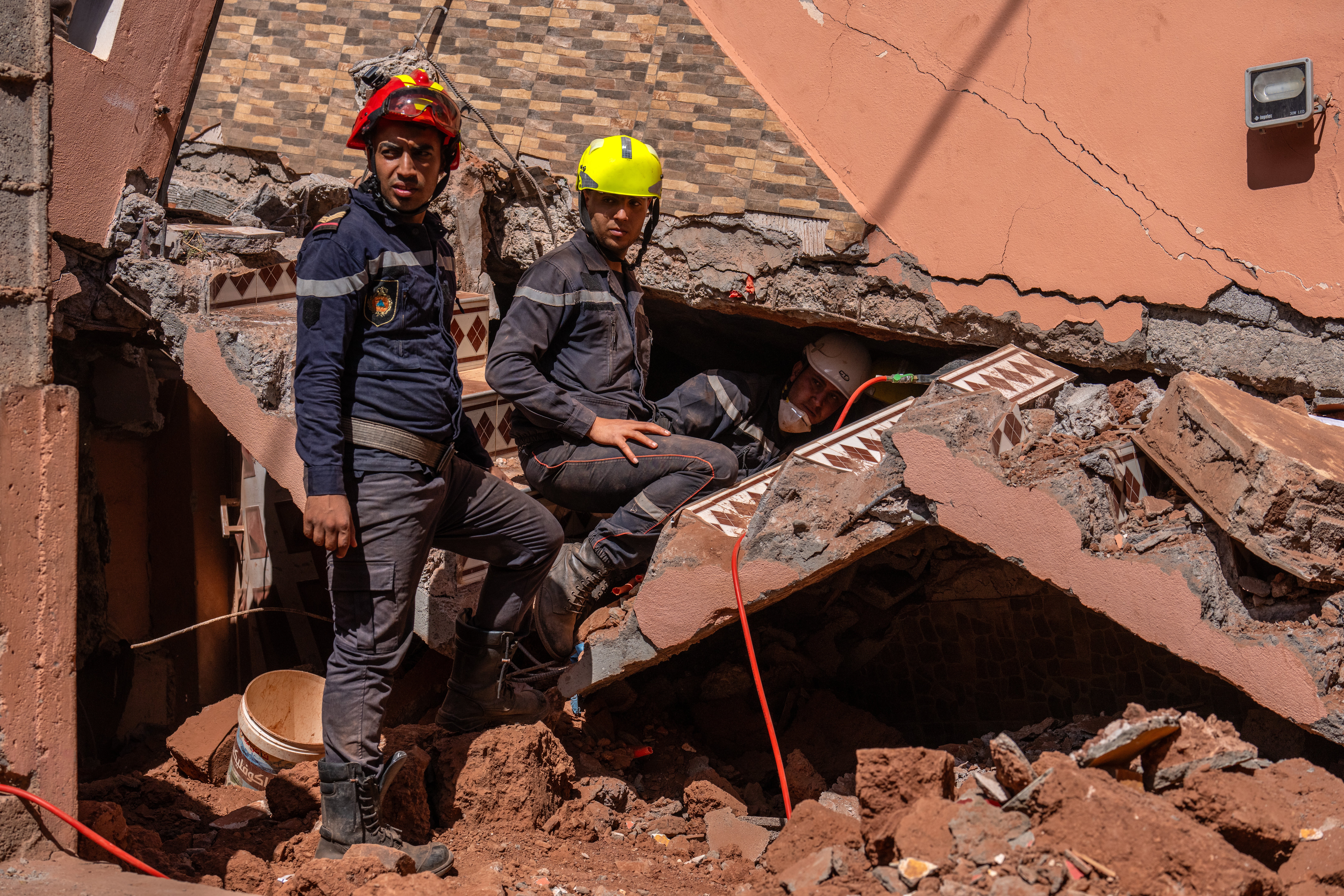 Emergency workers search beneath a heavily damaged house in Moulay Brahim, Morocco