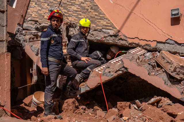 <p>Emergency workers search beneath a heavily damaged house in Moulay Brahim, Morocco</p>